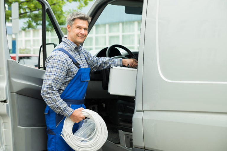 Handwerker steigt mit Werkzeugkoffer in einen Transporter