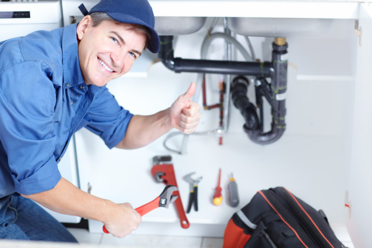 Sanitärinstallateur arbeitet an einem Abfluss unter dem Waschbecken
